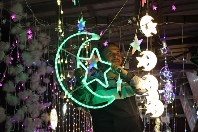 A Palestinian man hangs decorative lights at a shop in east Jerusalem on February 16, 2026, as Muslims prepare for the holy fasting month of Ramadan. Israeli police said on February 16 that they would deploy in force around Al-Aqsa Mosque during the Muslim holy month of Ramadan, which begins this week, as Palestinian officials accused Israel of imposing restrictions at the compound. (Photo by AHMAD GHARABLI / AFP)