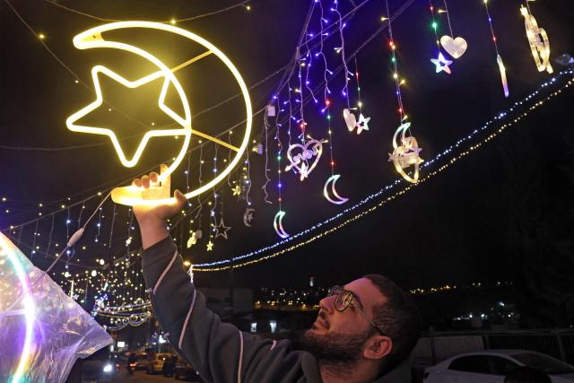 A Palestinian man hangs decorative lights at a shop in east Jerusalem on February 16, 2026, as Muslims prepare for the holy fasting month of Ramadan. Israeli police said on February 16 that they would deploy in force around Al-Aqsa Mosque during the Muslim holy month of Ramadan, which begins this week, as Palestinian officials accused Israel of imposing restrictions at the compound. (Photo by AHMAD GHARABLI / AFP)