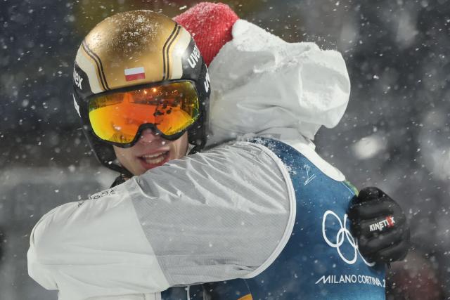 Poland's Kacper Tomasiak (L) and Poland's Pawel Wasek celebrate in the finish area after jumping during the final round of the men's large hill super team ski jumping of the Milano Cortina 2026 Winter Olympic Games at Predazzo Ski Jumping Stadium in Predazzo (Val di Fiemme), on February 16, 2026. (Photo by Anne-Christine POUJOULAT / AFP)