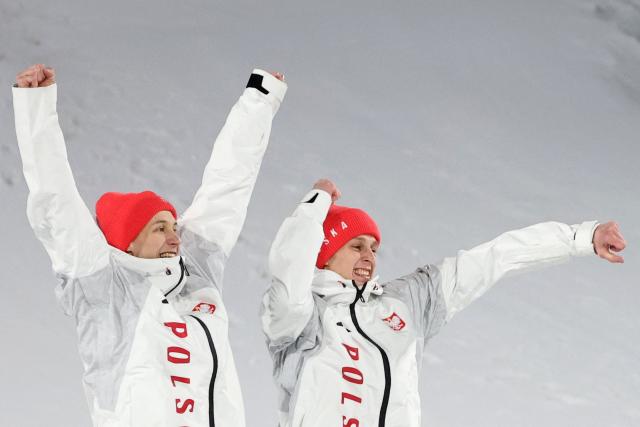 Silver medallists Poland's Kacper Tomasiak (L) and Poland's Pawel Wasek celebrate on the podium for the men's large hill super team ski jumping of the Milano Cortina 2026 Winter Olympic Games at Predazzo Ski Jumping Stadium in Predazzo (Val di Fiemme), on February 16, 2026. (Photo by Anne-Christine POUJOULAT / AFP)