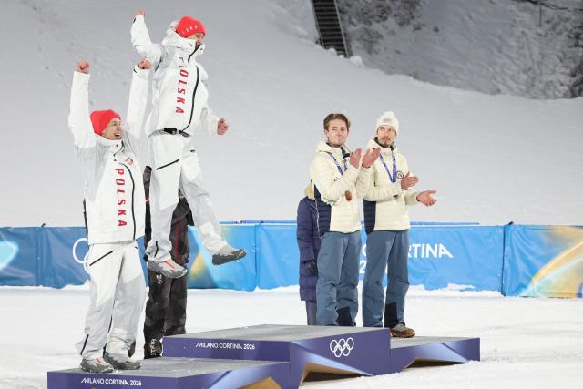 (fromL) Silver medallists Poland's Kacper Tomasiak, Poland's Pawel Wasek and bronze medallists Norway's Kristoffer Eriksen Sundal and Norway's Johann Andre Forfang celebrate on the podium for the men's large hill super team ski jumping of the Milano Cortina 2026 Winter Olympic Games at Predazzo Ski Jumping Stadium in Predazzo (Val di Fiemme), on February 16, 2026. (Photo by Anne-Christine POUJOULAT / AFP)