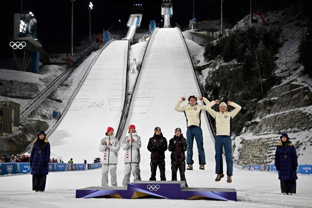 (from2ndL) Silver medallists Poland's Kacper Tomasiak, Poland's Pawel Wasek, gold medallists Austria's Stephan Embacher, Austria's Jan Hoerl, bronze medallists Norway's Kristoffer Eriksen Sundal and Norway's Johann Andre Forfang celebrate on the podium for the men's large hill super team ski jumping of the Milano Cortina 2026 Winter Olympic Games at Predazzo Ski Jumping Stadium in Predazzo (Val di Fiemme), on February 16, 2026. (Photo by Tobias SCHWARZ / AFP)