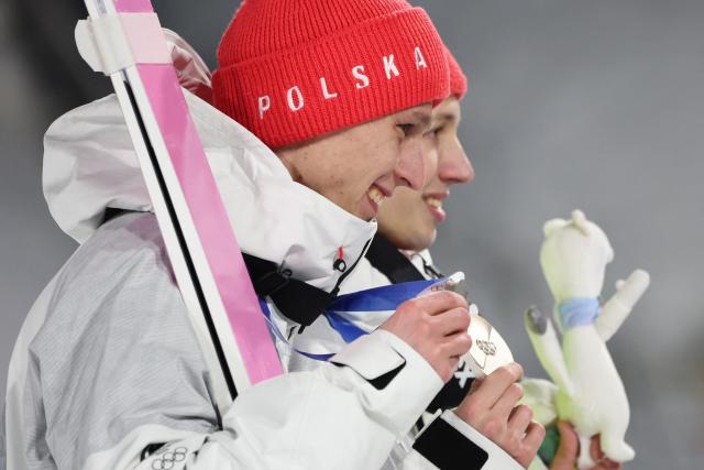 Silver medallists Poland's Pawel Wasek (L) and Poland's Kacper Tomasiak celebrate on the podium for the men's large hill super team ski jumping of the Milano Cortina 2026 Winter Olympic Games at Predazzo Ski Jumping Stadium in Predazzo (Val di Fiemme), on February 16, 2026. (Photo by Anne-Christine POUJOULAT / AFP)