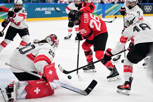 Switzerland's goalkeeper #20 Andrea Braendli saves a shot from Canada's forward #26 Emily Clark during the women's play-off semi-final ice hockey match between Canada and Switzerland at the Milano Santagiulia Ice Hockey Arena during the Milano Cortina 2026 Winter Olympic Games in Milan, on February 16, 2026. (Photo by Piero CRUCIATTI / AFP)