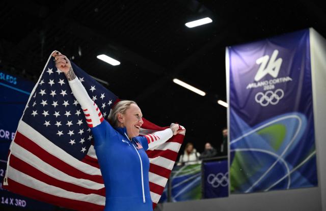 USA's Kaillie Armbruster Humphries holds an USA flag after competing to win bronze in the bobsleigh women's monobob heat 4 at Cortina Sliding Centre during the Milano Cortina 2026 Winter Olympic Games in Cortina d'Ampezzo on February 16, 2026. (Photo by Marco BERTORELLO / AFP)