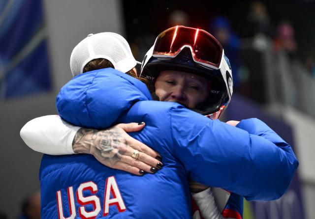 USA's Kaillie Armbruster Humphries is congratulated by a team member after competing to win bronze in the bobsleigh women's monobob heat 4 at Cortina Sliding Centre during the Milano Cortina 2026 Winter Olympic Games in Cortina d'Ampezzo on February 16, 2026. (Photo by Marco BERTORELLO / AFP)