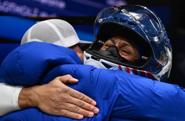 USA's Elana Meyers Taylor is congratulated by a teammate after competing to win gold in the bobsleigh women's monobob heat 4 at Cortina Sliding Centre during the Milano Cortina 2026 Winter Olympic Games in Cortina d'Ampezzo on February 16, 2026. (Photo by Marco BERTORELLO / AFP)