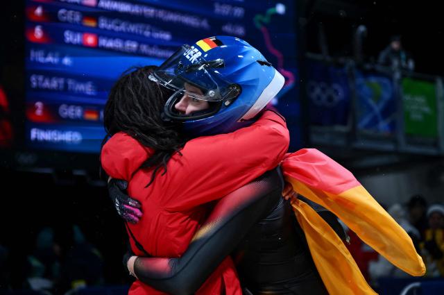 Germany's Laura Nolte is congratulated by a team member after winning silver in the bobsleigh women's monobob heat 4 at Cortina Sliding Centre during the Milano Cortina 2026 Winter Olympic Games in Cortina d'Ampezzo on February 16, 2026. (Photo by Marco BERTORELLO / AFP)