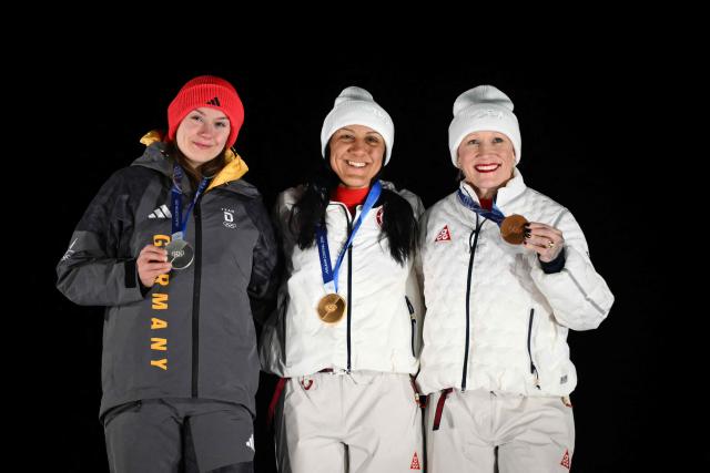 (L-R) Silver medallist Germany's Laura Nolte, gold medallist USA's Elana Meyers Taylor and bronze medallist USA's Kaillie Armbruster Humphries pose on the podium of the bobsleigh women's monobob at Cortina Sliding Centre during the Milano Cortina 2026 Winter Olympic Games in Cortina d'Ampezzo on February 16, 2026. (Photo by Marco BERTORELLO / AFP)