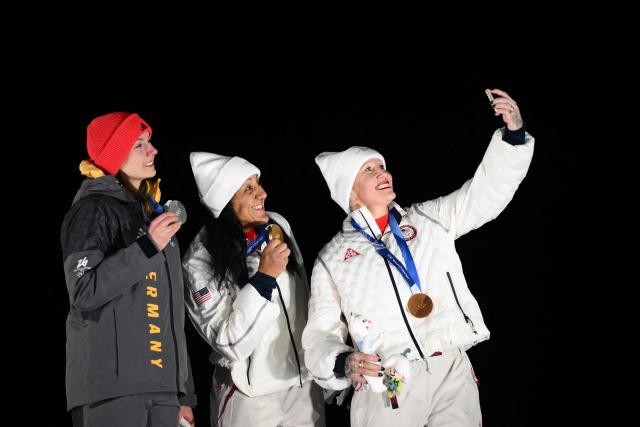 (L-R) Silver medallist Germany's Laura Nolte, gold medallist USA's Elana Meyers Taylor and bronze medallist USA's Kaillie Armbruster Humphries pose for a selfie on the podium of the bobsleigh women's monobob at Cortina Sliding Centre during the Milano Cortina 2026 Winter Olympic Games in Cortina d'Ampezzo on February 16, 2026. (Photo by Marco BERTORELLO / AFP)