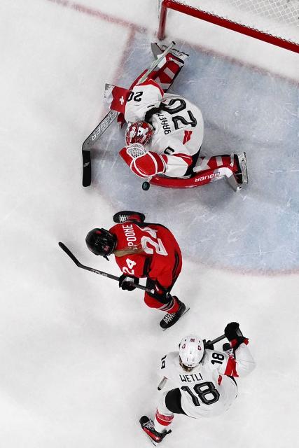 Switzerland's goalkeeper #20 Andrea Braendli (up) makes a save during the women's play-off semi-final ice hockey match between Canada and Switzerland at the Milano Santagiulia Ice Hockey Arena during the Milano Cortina 2026 Winter Olympic Games in Milan, on February 16, 2026. (Photo by Alexander NEMENOV / AFP)
