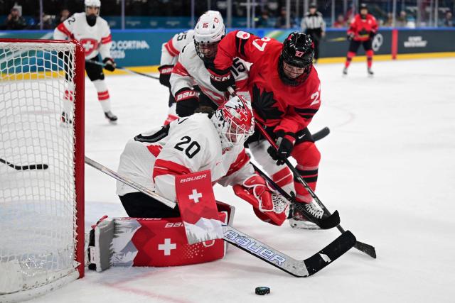 Switzerland's goalkeeper #20 Andrea Braendli (L) makes a save during the women's play-off semi-final ice hockey match between Canada and Switzerland at the Milano Santagiulia Ice Hockey Arena during the Milano Cortina 2026 Winter Olympic Games in Milan, on February 16, 2026. (Photo by Piero CRUCIATTI / AFP)
