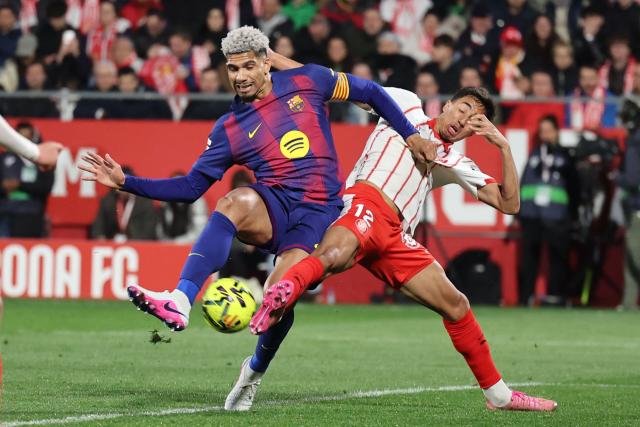Barcelona's Uruguayan defender #04 Ronald Federico Araujo da Silva (L) and Girona's Brazilian defender #12 Vitor Reis fight for the ball during the Spanish league football match between Girona FC and FC Barcelona at Montilivi Stadium in Girona on February 16, 2026. (Photo by Josep LAGO / AFP)