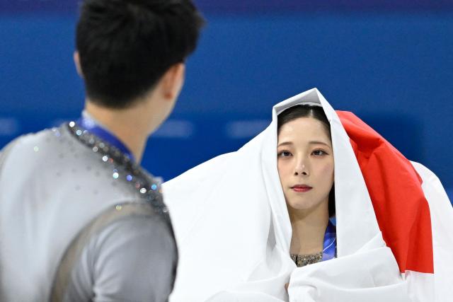 Gold medallist Japan's Riku Miura holds a Japanese flag after the figure skating pair skating free skating final during the Milano Cortina 2026 Winter Olympic Games at Milano Ice Skating Arena in Milan on February 16, 2026. (Photo by WANG Zhao / AFP)