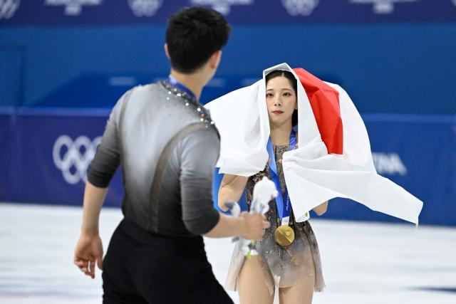 Gold medallist Japan's Riku Miura holds a Japanese flag after the figure skating pair skating free skating final during the Milano Cortina 2026 Winter Olympic Games at Milano Ice Skating Arena in Milan on February 16, 2026. (Photo by WANG Zhao / AFP)