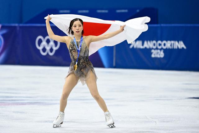 Gold medallist Japan's Riku Miura holds a Japanese flag after the figure skating pair skating free skating final during the Milano Cortina 2026 Winter Olympic Games at Milano Ice Skating Arena in Milan on February 16, 2026. (Photo by WANG Zhao / AFP)