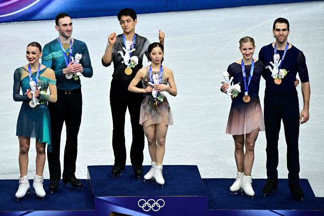 Silver medallists (L) Georgia's Anastasiia Metelkina and Luka Berulava, gold medallists (C) Japan's Riku Miura and Ryuichi Kihara and bronze medallists (R) Germany's Minerva Fabienne Hase and Nikita Volodin pose after the victory ceremony of the figure skating pair skating free skating final during the Milano Cortina 2026 Winter Olympic Games at Milano Ice Skating Arena in Milan on February 16, 2026. (Photo by JULIEN DE ROSA / AFP)