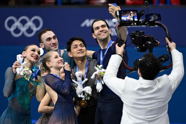 Silver medallists Georgia's Anastasiia Metelkina and Georgia's Luka Berulava, gold medallists Japan's Riku Miura and Japan's Ryuichi Kihara, and bronze medallists Germany's Minerva Fabienne Hase and Germany's Nikita Volodin pose for a selfie on the podium of the figure skating pair skating free skating final during the Milano Cortina 2026 Winter Olympic Games at Milano Ice Skating Arena in Milan on February 16, 2026. (Photo by WANG Zhao / AFP)