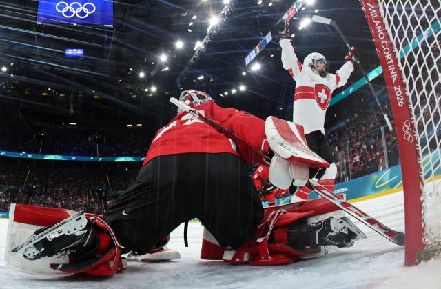 Switzerland's forward #21 Rahel Enzler (R) celebrates after scoring her team's first goal against Canada's goalkeeper #35 Ann-Renee Desbiens during the women's play-off semi-final ice hockey match between Canada and Switzerland at the Milano Santagiulia Ice Hockey Arena during the Milano Cortina 2026 Winter Olympic Games in Milan, on February 16, 2026. (Photo by POOL / AFP)