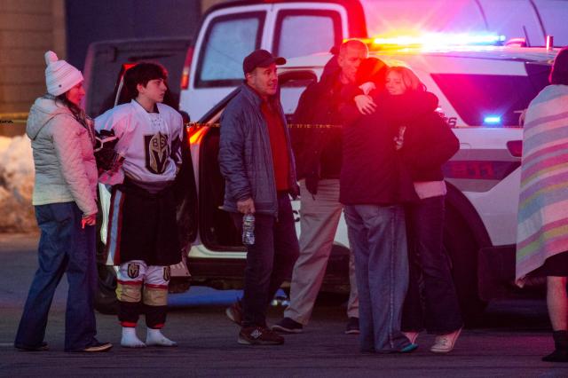 People embrace and walk away as police stand outside the perimeter they created around the Dennis M. Lynch Arena where a shooting occurred earlier today in Pawtucket, Rhode Island, on February 16, 2026. At least two people were killed and three wounded in a shooting at an ice rink in the northeastern US town of Pawtucket on Monday, authorities said, with social media footage showing frightened teenagers fleeing the sound of gunshots. "We have three deceased. The suspect, and then we have two victims, and then we have three at the hospital," said Pawtucket police chief Tina Goncalves told reporters after the incident. She added that initial investigations suggested the shooting was targeted and "may be a family dispute." (Photo by Joseph Prezioso / AFP)