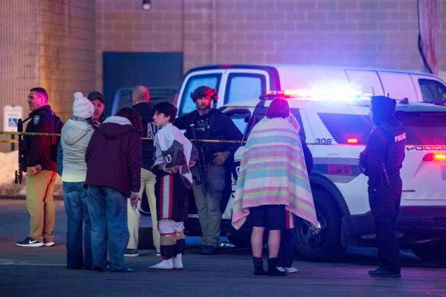 People stand outside a police perimeter they created around the Dennis M. Lynch Arena where a shooting occurred earlier today in Pawtucket, Rhode Island, on February 16, 2026. At least two people were killed and three wounded in a shooting at an ice rink in the northeastern US town of Pawtucket on Monday, authorities said, with social media footage showing frightened teenagers fleeing the sound of gunshots. "We have three deceased. The suspect, and then we have two victims, and then we have three at the hospital," said Pawtucket police chief Tina Goncalves told reporters after the incident. She added that initial investigations suggested the shooting was targeted and "may be a family dispute." (Photo by Joseph Prezioso / AFP)