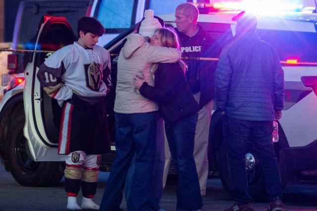 People embrace and walk away as police stand outside the perimeter they created around the Dennis M. Lynch Arena where a shooting occurred earlier today in Pawtucket, Rhode Island, on February 16, 2026. At least two people were killed and three wounded in a shooting at an ice rink in the northeastern US town of Pawtucket on Monday, authorities said, with social media footage showing frightened teenagers fleeing the sound of gunshots. "We have three deceased. The suspect, and then we have two victims, and then we have three at the hospital," said Pawtucket police chief Tina Goncalves told reporters after the incident. She added that initial investigations suggested the shooting was targeted and "may be a family dispute." (Photo by Joseph Prezioso / AFP)