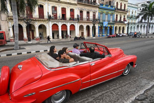 (FILES) Tourists ride in an old American car used as a taxi in Havana on February 2, 2026. Cuba's already shattered economy is being assailed on various fronts as US President Donald Trump has vowed to bring the communist island to its knees. A blockade of oil deliveries to Cuba has forced emergency rationing, kneecapping the country's critical tourism and tobacco sectors even as remittances are under threat and income earned from sending doctors abroad has been all but cut off. (Photo by YAMIL LAGE / AFP)