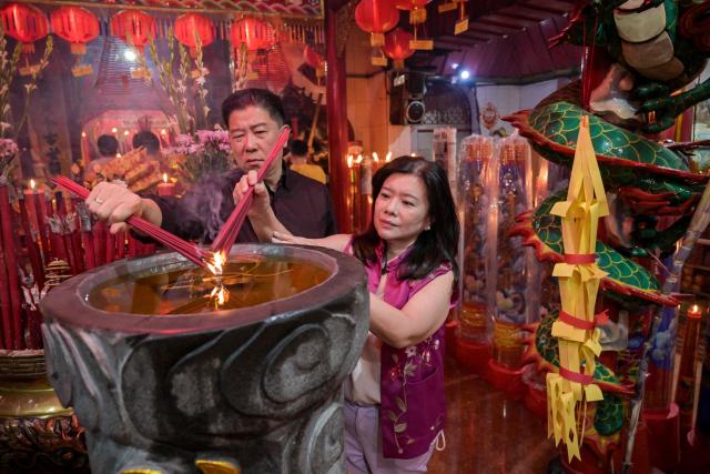 People burn incense sticks as they offer prayers on the first day of the Lunar New Year of the Horse at Hong San Koo Tee temple in Surabaya on February 17, 2026. (Photo by JUNI KRISWANTO / AFP)