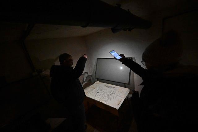 A map is illuminated with cell phone flashlights at the second civil defense shelter during a visit with AFP journalists in Nitra, Slovakia, on January 13, 2026. The war in neighbouring Ukraine feels distant to many in the Slovak city of Nitra but the local council is preparing for the worst and revamping its Cold War-era nuclear fallout shelters. (Photo by Joe Klamar / AFP)