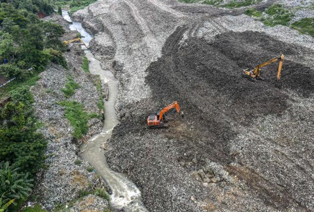 This aerial picture taken on January 15, 2026, shows excavators going through a pile of waste at the Cipayung landfill that frequently collapses, blocking the flow of a nearby river in Depok, West Java. Garbage-choked streets, overloaded landfills and the fear of trash avalanches haunt greater Jakarta, as the world's most populous metropolis grapples with a waste crisis. (Photo by BAY ISMOYO / AFP) / To go with 'INDONESIA-ENVIRONMENT-WASTE-CRISIS,FOCUS' by Dessy SAGITA