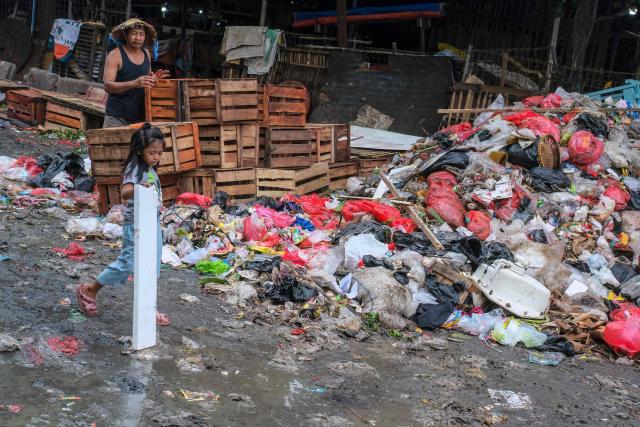 This picture taken on January 20, 2026, shows a child carrying an item scavenged from a pile of trash on a public road in Pasar Minggu, Jakarta. Garbage-choked streets, overloaded landfills and the fear of trash avalanches haunt greater Jakarta, as the world's most populous metropolis grapples with a waste crisis. (Photo by BAY ISMOYO / AFP) / To go with 'INDONESIA-ENVIRONMENT-WASTE-CRISIS,FOCUS' by Dessy SAGITA