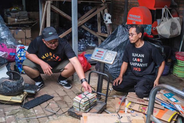 This picture taken on February 4, 2026, shows Wahyu Eka Styawan (L) from the environmental group WALHI speaking with Safari (R), the head of a waste bank that purchases waste brought by the community, in Jakarta. Garbage-choked streets, overloaded landfills and the fear of trash avalanches haunt greater Jakarta, as the world's most populous metropolis grapples with a waste crisis. (Photo by BAY ISMOYO / AFP) / To go with 'INDONESIA-ENVIRONMENT-WASTE-CRISIS,FOCUS' by Dessy SAGITA