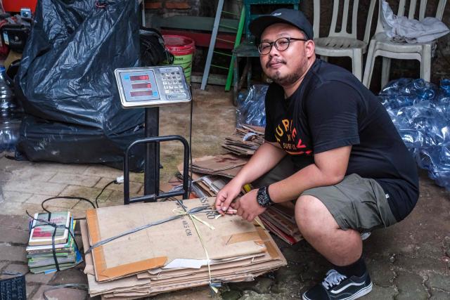This picture taken on February 4, 2026, shows Wahyu Eka Styawan from the environmental group WALHI posing in front of a pile of waste at a waste bank that purchases recyclable material brought by the community, in Jakarta. Garbage-choked streets, overloaded landfills and the fear of trash avalanches haunt greater Jakarta, as the world's most populous metropolis grapples with a waste crisis. (Photo by BAY ISMOYO / AFP) / To go with 'INDONESIA-ENVIRONMENT-WASTE-CRISIS,FOCUS' by Dessy SAGITA