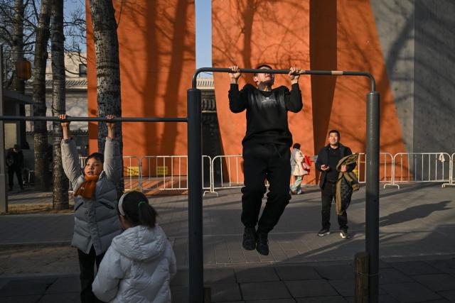 This picture taken on February 4, 2026 shows people working out at Ritan Park in Beijing. Fifteen years ago, Beijing's Liangma riverbanks would have been smog-choked and deserted in winter, but these days they are dotted with families and exercising pensioners most mornings. The turnaround is the result of a years-long campaign that threw China's state power behind policies like moving factories and electrifying vehicles to improve some the world's worst air pollution. (Photo by Pedro PARDO / AFP) / To go with AFP story China-environment-air pollition-politics, FOCUS by Peter Catterall and Rebecca Bailey