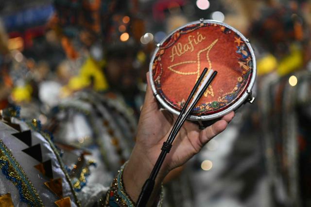 A reveller of the Beija-Flor de Nipolis samba school plays a pandeiro during the second night of the Rio Carnival at the Marques de Sapucai Sambadrome in Rio de Janeiro, Brazil, early on February 17, 2026. (Photo by Mauro PIMENTEL / AFP)