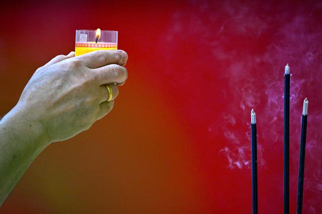 A man burns a candle and incense as he prays at a temple on the first day of the Lunar New Year of the Horse in Banda Aceh, Indonesia's Aceh province on February 17, 2026. (Photo by CHAIDEER MAHYUDDIN / AFP/Chaideer MAHYUDDIN / AFP)