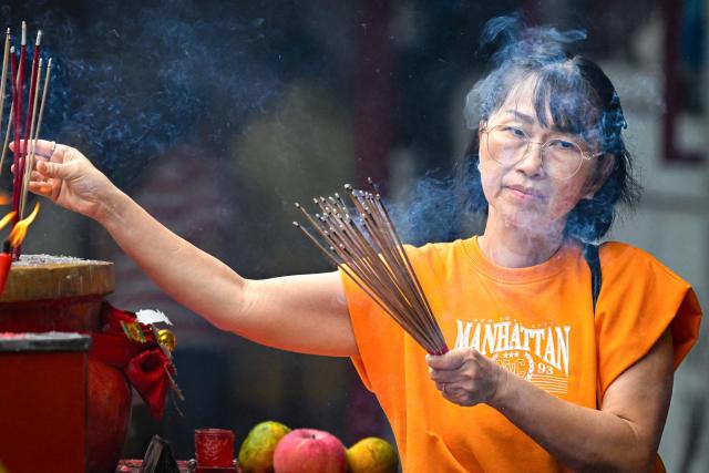 A woman burns incense as she prays at a temple on the first day of the Lunar New Year of the Horse in Banda Aceh, Indonesia's Aceh province on February 17, 2026. (Photo by CHAIDEER MAHYUDDIN / AFP/Chaideer MAHYUDDIN / AFP)