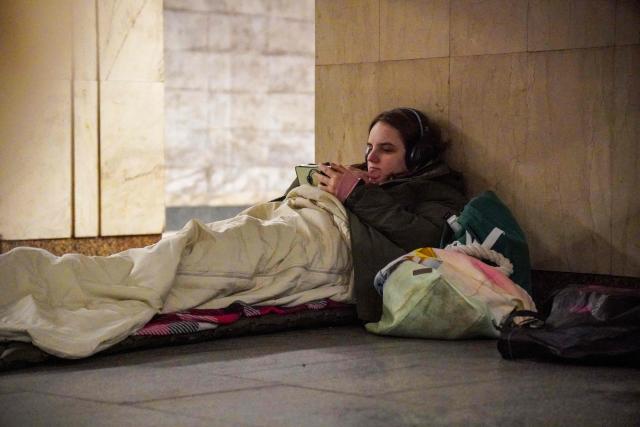 A girl looks at her phone as she takes shelter at a metro station during an air raid alert, in Kyiv, early on February 17, 2026, amid the Russian invasion of Ukraine. (Photo by Serhii Okunev / AFP)