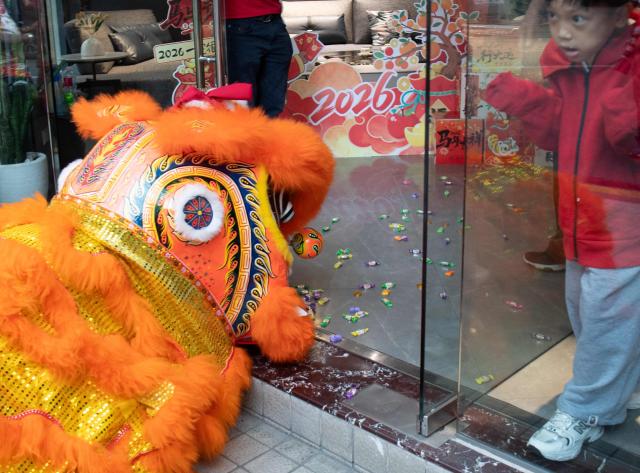 A young boy watches a lion dance group perform along a street during the first day of the Lunar New Year of the Horse in the Chinatown district of Manila on February 17, 2026. (Photo by Ted ALJIBE / AFP)