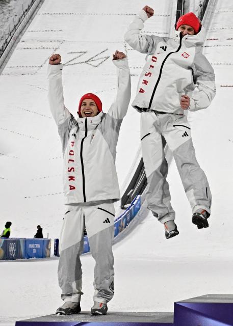 Silver medallists Poland's Kacper Tomasiak (L) and Poland's Pawel Wasek celebrate on the podium for the men's large hill super team ski jumping of the Milano Cortina 2026 Winter Olympic Games at Predazzo Ski Jumping Stadium in Predazzo (Val di Fiemme), on February 16, 2026. (Photo by Tobias SCHWARZ / AFP)