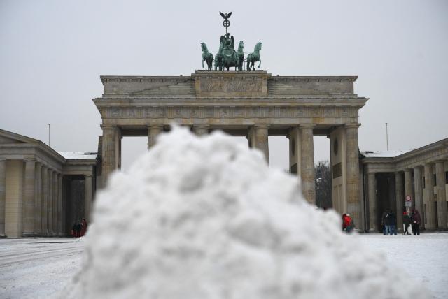 Tourists walk past ploughed snow in front of the Brandenburg Gate in Berlin, on February 17, 2026 after new snowfall. (Photo by RALF HIRSCHBERGER / AFP)