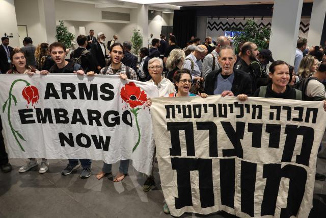 Israeli left-wing demonstrators hold banners during a protest against the arms industry at an international arms and security fair in Tel Aviv on February 17, 2026. (Photo by JACK GUEZ / AFP)