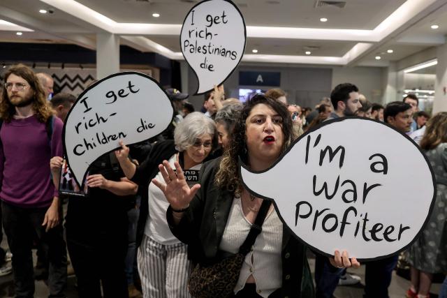 Israeli left-wing demonstrators hold placards during a protest against the arms industry at an international arms and security fair in Tel Aviv on February 17, 2026. (Photo by JACK GUEZ / AFP)