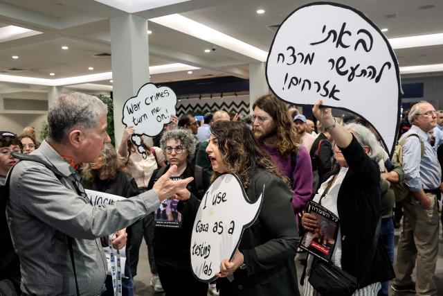 Israeli left-wing demonstrators argue with a man as they hold placards during a protest against the arms industry at an international arms and security fair in Tel Aviv on February 17, 2026. (Photo by JACK GUEZ / AFP)