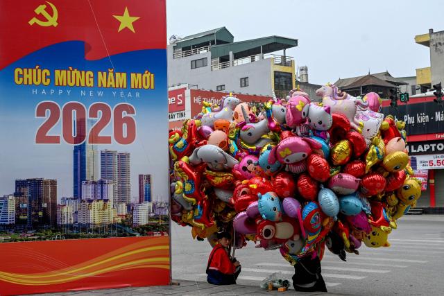 A young man sits selling balloons on a street on the first day of the Lunar New Year or Tet in Hanoi on February 17, 2026. (Photo by Nhac NGUYEN / AFP)
