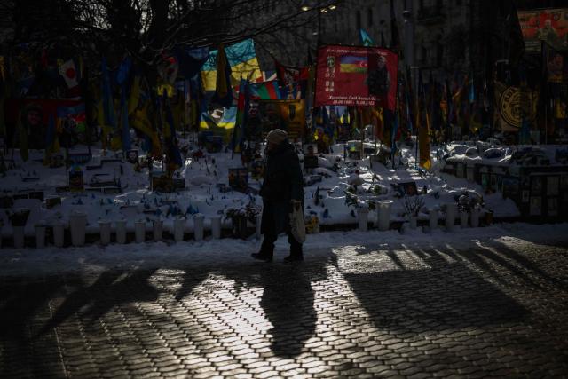 A person walks past a makeshift memorial for fallen Ukrainian and foreign soldiers in Independence Square in Kyiv on February 17, 2026, amid the Russian invasion of Ukraine. (Photo by HENRY NICHOLLS / AFP)