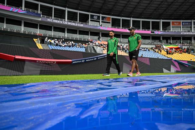 TOPSHOT - Zimbabwe's captain Sikandar Raza (L) inspects the covered pitch as rain delays the start of the 2026 ICC Men's T20 Cricket World Cup group stage match between Zimbabwe and Ireland at Pallekele International Cricket Stadium in Kandy on February 17, 2026. (Photo by Ishara S. KODIKARA / AFP)
