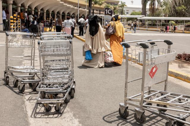 Stranded passengers walk past empty trolleys on the walk way next to a closed door at the departures of the Jomo Kenyatta International Airport (JKIA) in Nairobi on February 17, 2026 amid a strike by the Kenyan Aviation Workers Union (KAWU). Passengers were stranded at the Jommo Kenyatta International Aiport (JKIA) on Tuesday as a strike by air traffic controllers entered a second day, leaving many travellers waiting for hours. A worker's strike disrupted flights and air traffic control operations at Kenya's main airport on Monday, the national carrier said.
Kenya Airways (KQ) warned passengers of "possible schedule adjustments, including delays" and advised them not to proceed to the airport without first confirming their flight status. (Photo by SIMON MAINA / AFP)