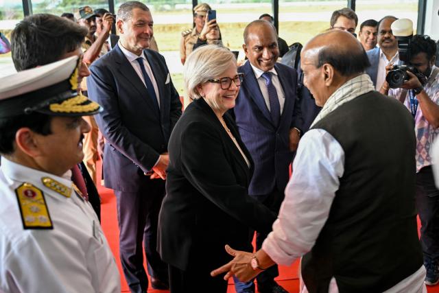 India's Defence Minister Rajnath Singh (R) greets French Defence Minister Catherine Vautrin (C) ahead of the virtual inauguration of the H125 Light Utility Helicopter's Final Assembly Line (FAL) facility of Tata-Airbus at Vemagal on February 17, 2026. Indian Prime Minister Narendra Modi and French President Emmanuel Macron will inaugurate, via video conference on February 17, India's first helicopter final assembly line, a joint venture between India's Tata Group and Airbus. (Photo by Idrees MOHAMMED / AFP)