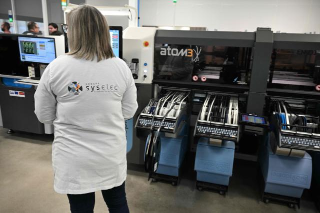 An employee works at an assembly line at Syselec group's factory, which produces printed circuit boards, in Castres, southwestern France, on February 17, 2026. (Photo by Lionel BONAVENTURE / AFP)